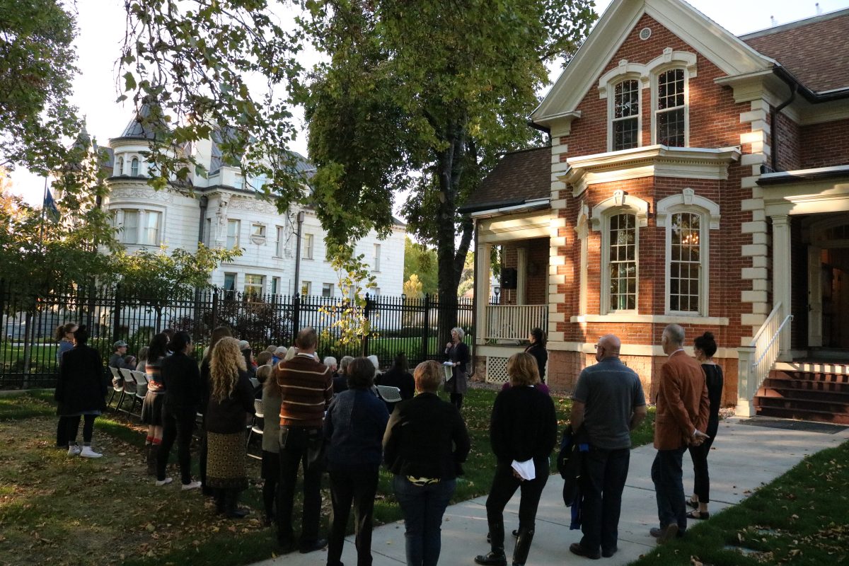 A two-story, red brick building with a crowd gathered.