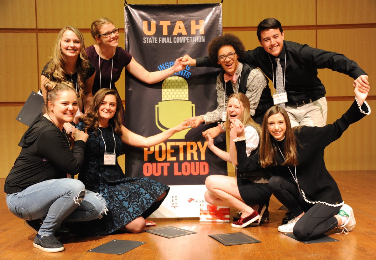 A group of students posing in front of a Poetry Out Loud banner.