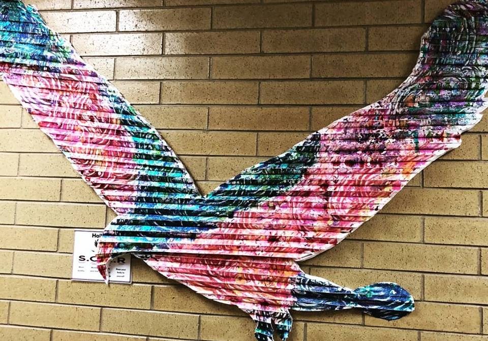 An image of a colorful eagle on a brick wall.