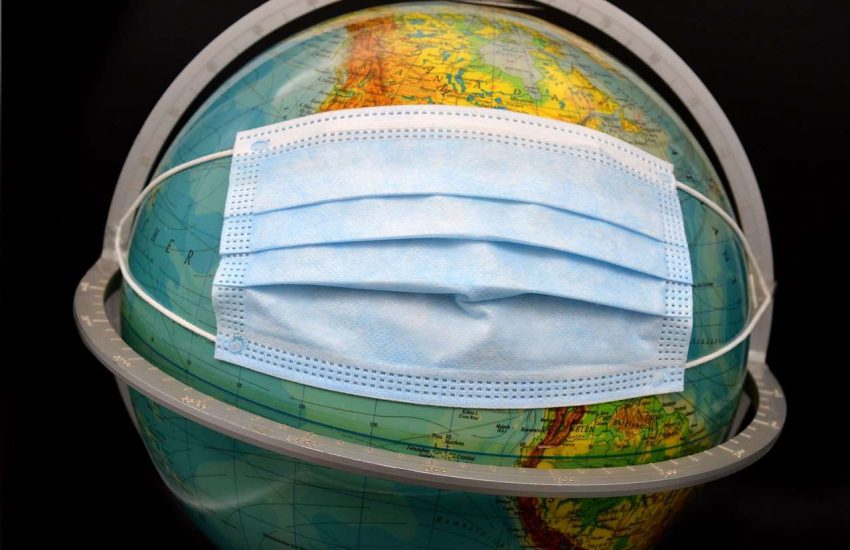 An image of a world globe with a blue surgical mask attached as though it is being worn.
