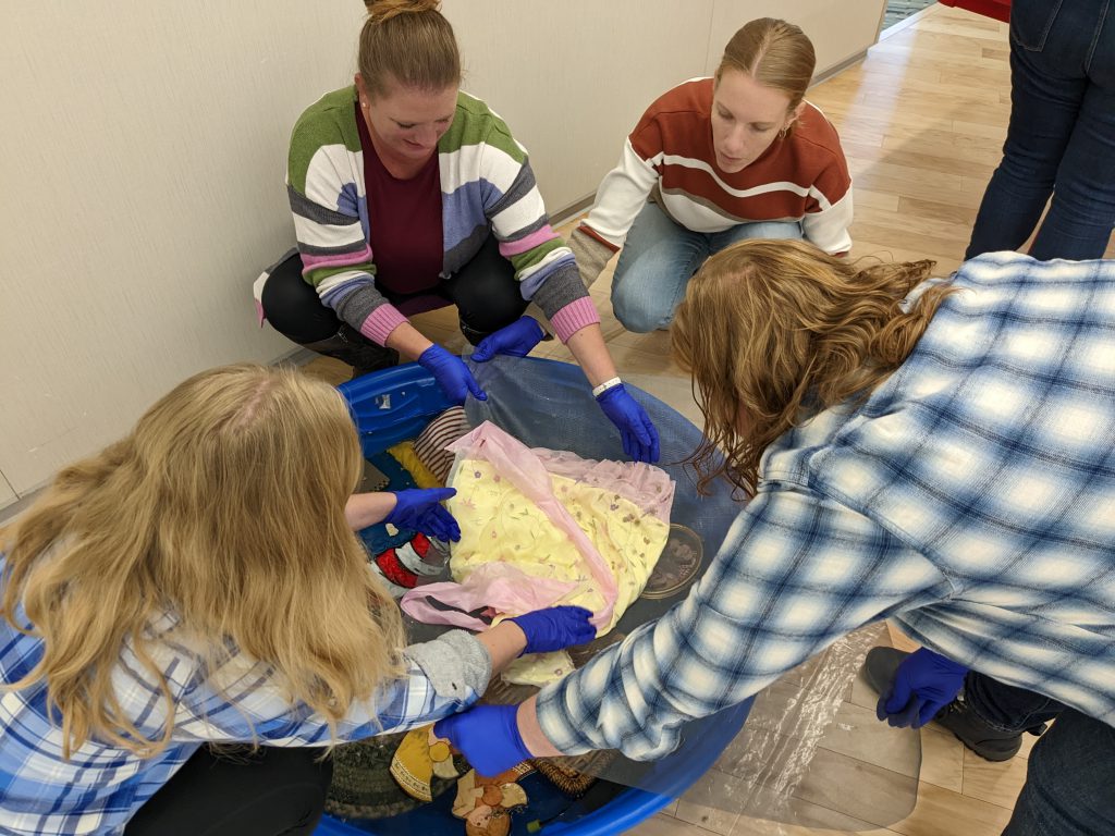 A group with gloves examining an artifact.